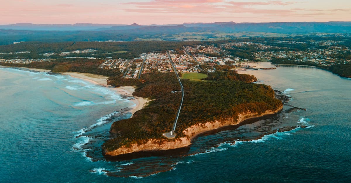 Stunning aerial shot of Ulladulla, NSW coast at sunset showcasing town, forest, and ocean scenery.